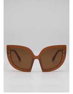 Dettaglio di occhiali da sole cat-eye oversize con montatura marrone e rivetti in metallo