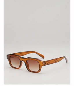 Macro detail of amber tortoiseshell sunglasses frame with premium metal hinges and brown lenses