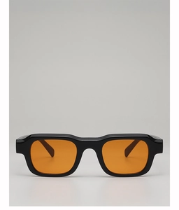 Close-up of thick black rectangular frames with vibrant orange lenses in studio lighting
