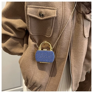 Detail of blue rhinestone evening bag with gold chain strap and metallic handle