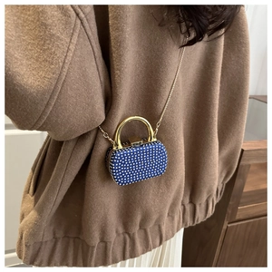 Close-up of a blue evening clutch bag with white rhinestones and a gold metal handle