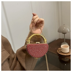 Close-up of a red rhinestone evening clutch bag with gold handle held in hand