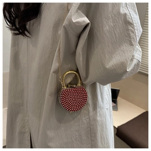 Detail of red rhinestone evening bag featuring gold handle and elegant chain strap