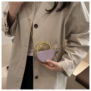 Detail of lavender pearl evening bag featuring gold ring handle and metal chain strap