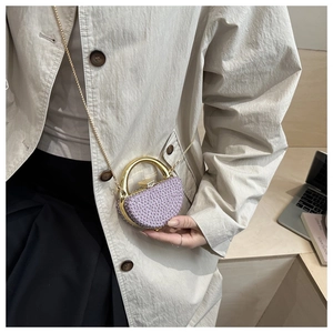 Detail of purple beaded evening bag with golden circular handle and elegant metal chain