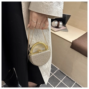 Close-up of heart-shaped evening clutch bag with sparkling pearls and gold metal chain