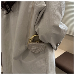 Sparkling heart-shaped evening bag with rhinestones and gold handle shown on a shoulder