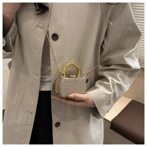 Detailed shot of mini evening clutch with pearls, gold handle and chain on model