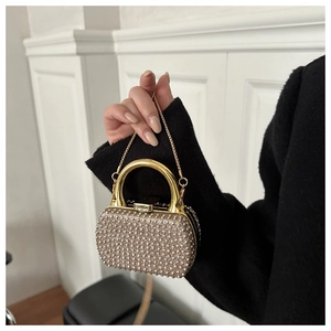 Close-up of a mini evening clutch featuring silver rhinestones and a gold metal handle