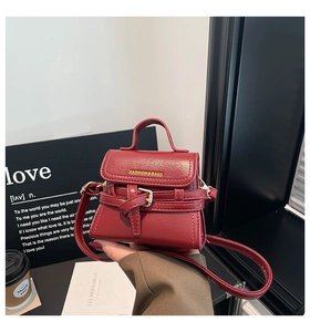 Dettaglio di una mini borsa a tracolla in pelle rossa con fibbia dorata e scritte