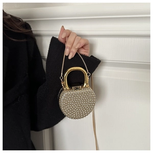 Close-up of a mini round rhinestone evening clutch with gold handle and chain strap
