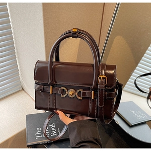 Gros plan sur un sac à main vintage marron foncé avec fermoir cœur doré et fini brillant