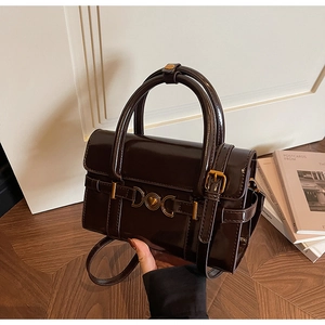 Détail d'un sac à main en cuir verni marron foncé avec boucle dorée en forme de cœur