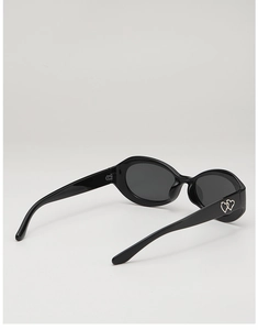 Détail de lunettes de soleil ovales avec accents métalliques double cœur sur la branche noire
