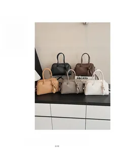 Détail de cinq sacs en cuir colorés avec poignées nouées et texture grainée lychee
