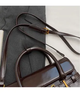 Détail de la bandoulière réglable et de la finition en cuir brillant sur le sac à main