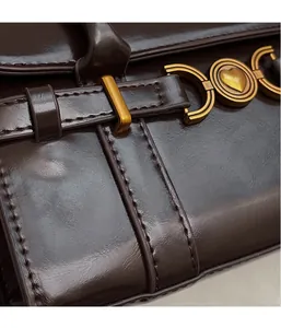 Détail du sac en cuir marron foncé avec boucle coeur dorée et coutures soignées