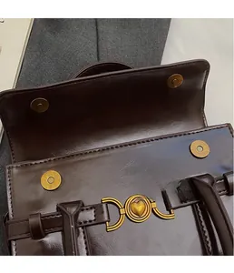 Gros plan du fermoir magnétique et de la boucle en forme de cœur sur un sac à main marron