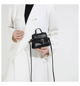 Dettaglio mini borsa nera con trama a litchi e fibbia su blazer bianco chic