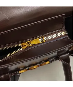 Gros plan d'une fermeture éclair en métal doré sur un sac à main en cuir marron