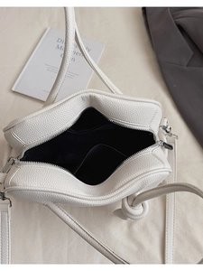 Vue de dessus d'un sac carré en cuir blanc montrant la doublure et la poche intérieure
