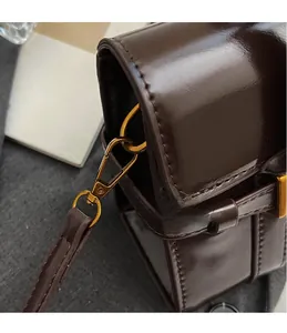 Détail d'un sac en cuir marron foncé avec crochet métallique doré de style vintage