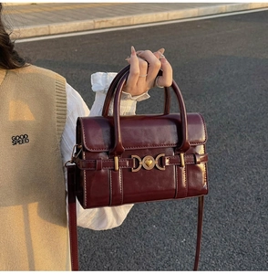 Détail de la boucle cœur vintage bordeaux sur un sac à main en cuir verni brillant