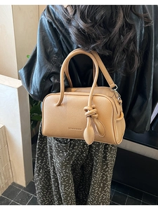 Détail du sac à main en cuir grainé marron clair avec nœud tressé élégant sur l'anse