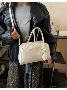 Détail du sac bandoulière en cuir grainé blanc avec breloque nœud et texte logo