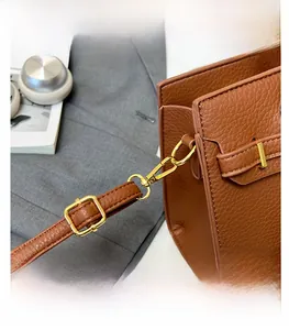 Détail d'un sac en cuir marron avec crochet en métal doré et bandoulière réglable