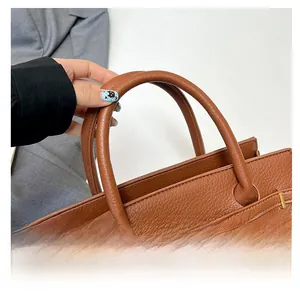Gros plan sur la poignée renforcée et les ferrures dorées du sac à main en cuir marron