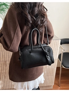 Détail du sac carré en cuir noir grainé avec poignées nouées et texture gaufrée chic