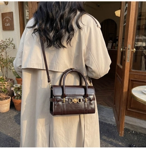 Vue arrière du mannequin portant un sac bandoulière rétro marron foncé et doré