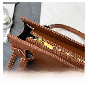 Détail macro de la fermeture éclair en métal doré sur un sac à main en cuir marron