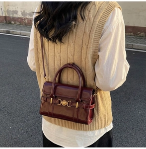 Détail du sac à main brillant bordeaux avec boucle cœur dorée sur fond extérieur élégant