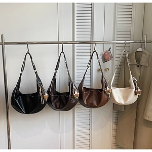 Detail van vier hobo-tassen in diverse kleuren hangend aan een rek met beer-hangers