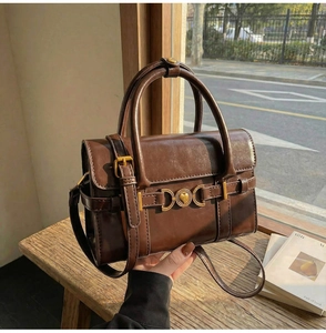 Détail du sac à main vintage marron avec boucle en cœur et éléments de quincaillerie en métal