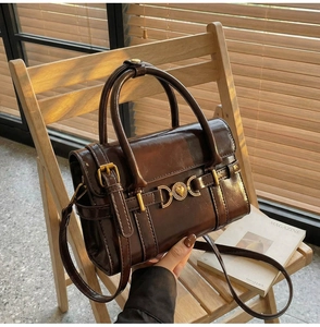 Gros plan du sac vintage marron foncé avec fermoir cœur doré sur chaise en bois
