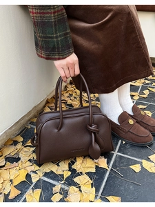 Détail du sac Boston en cuir marron foncé avec breloque feuille et décor automnal