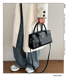 Détail du sac à main en cuir grainé noir avec fermoir doré et bandoulière amovible