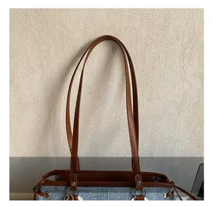 Detalle del bolso tote denim con costuras y fijación del asa de cuero sintético marrón