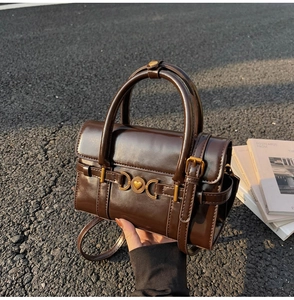 Détail du sac à main vintage marron foncé avec boucle coeur dorée sur fond urbain
