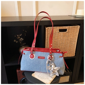 Detail of blue denim shoulder bag with red contrast trim and silver star charm
