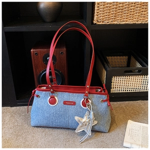 Detail of denim bowling bag with red leather trim and silver star pendant accessory