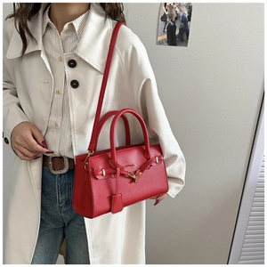 Gros plan du sac à main rouge en cuir grainé avec boucle dorée sur un trench-coat blanc
