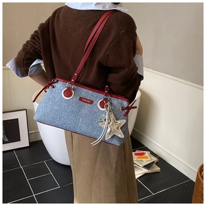 Detail of blue denim shoulder bag with red leather trim and a silver star charm