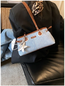 Detail of light blue denim shoulder bag with brown leather trim and starfish charm