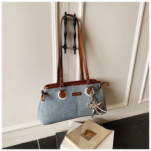 Detail of denim shoulder bag with leather trim, fashion metal logo, and star pendant