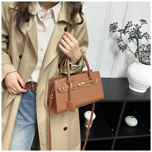 Détail du sac en cuir marron à motif litchi avec fermoir doré et poignée élégante