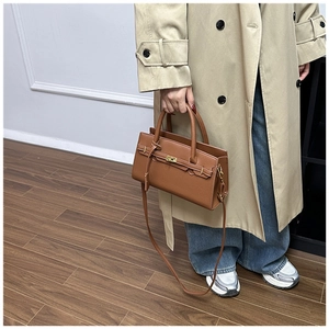 Close-up of caramel brown lychee grain leather handbag with gold metal twist lock buckle